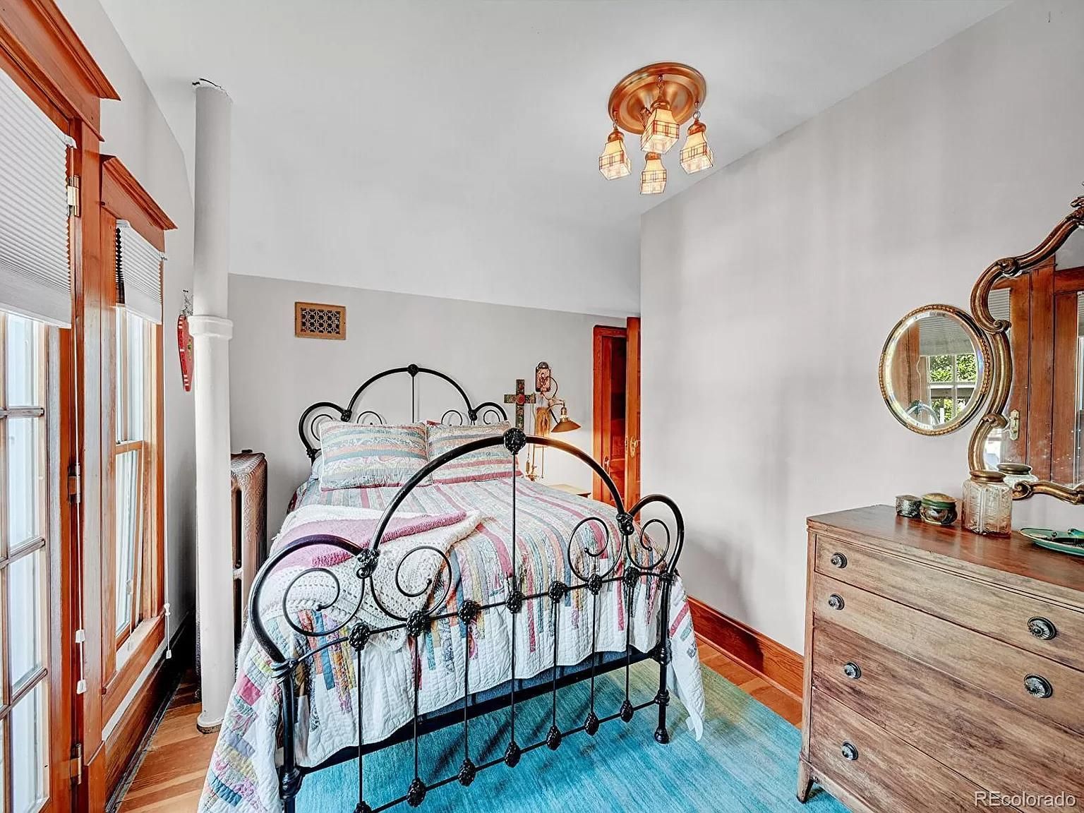 A bedroom with a bed , dresser , mirror and window.