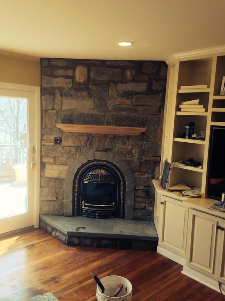A living room with a stone fireplace and built in shelves