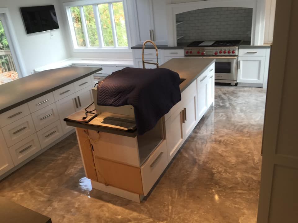 A kitchen with white cabinets and a large island in the middle