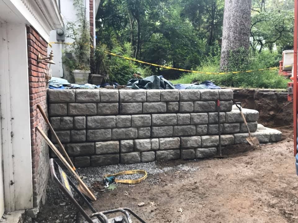 A brick wall is being built in the backyard of a house.