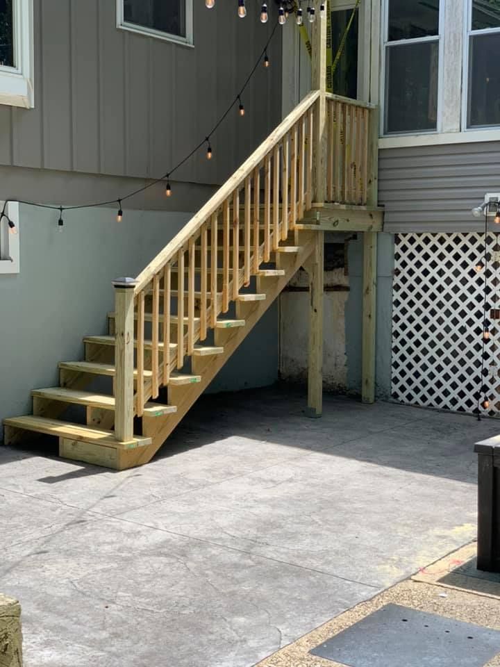 A wooden staircase leading up to a deck in front of a house.