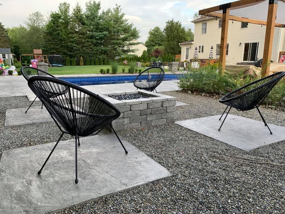 A group of chairs are sitting next to a fire pit in a backyard.