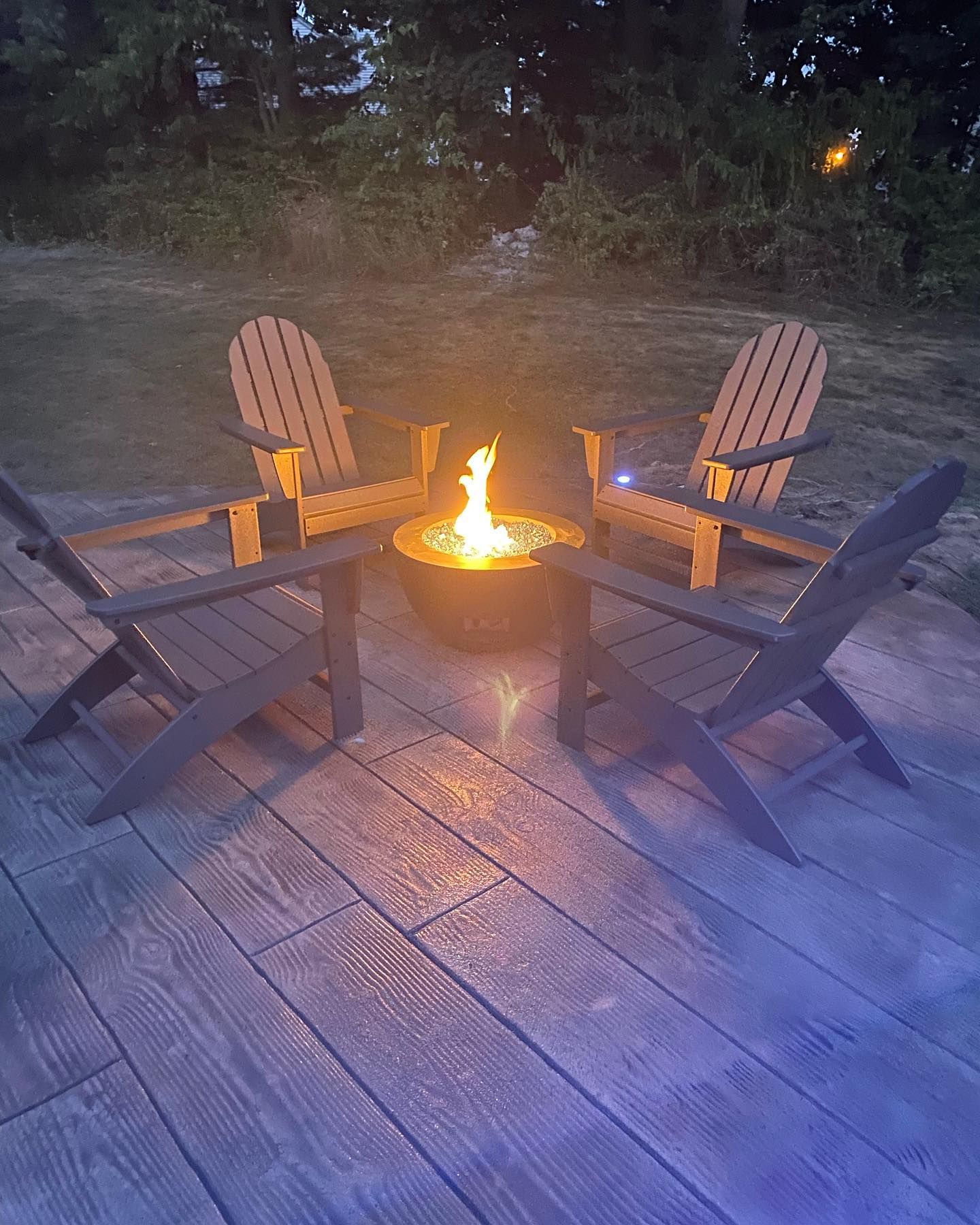 Two adirondack chairs are sitting next to a fire pit on a deck.
