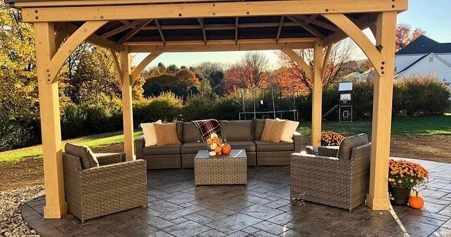 A wooden gazebo with wicker furniture underneath it