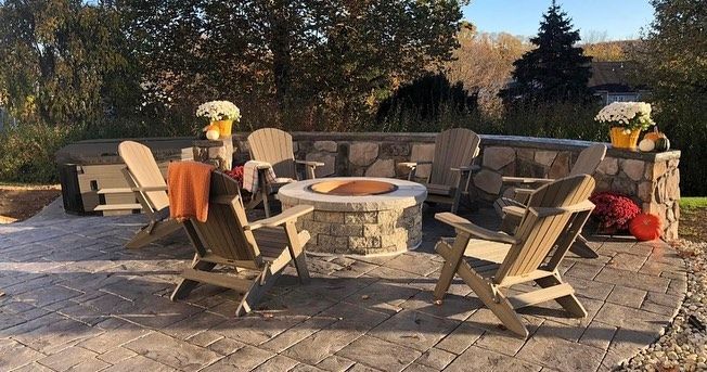 A group of chairs are sitting around a fire pit on a patio.