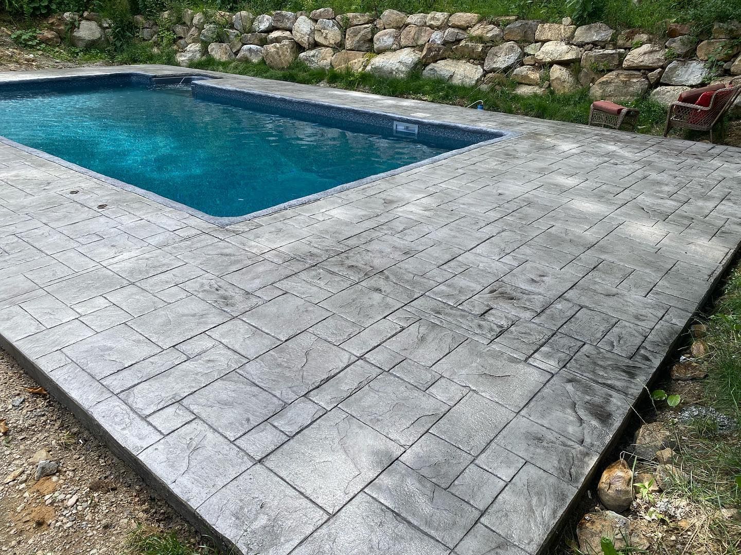 A large swimming pool is surrounded by a concrete patio.