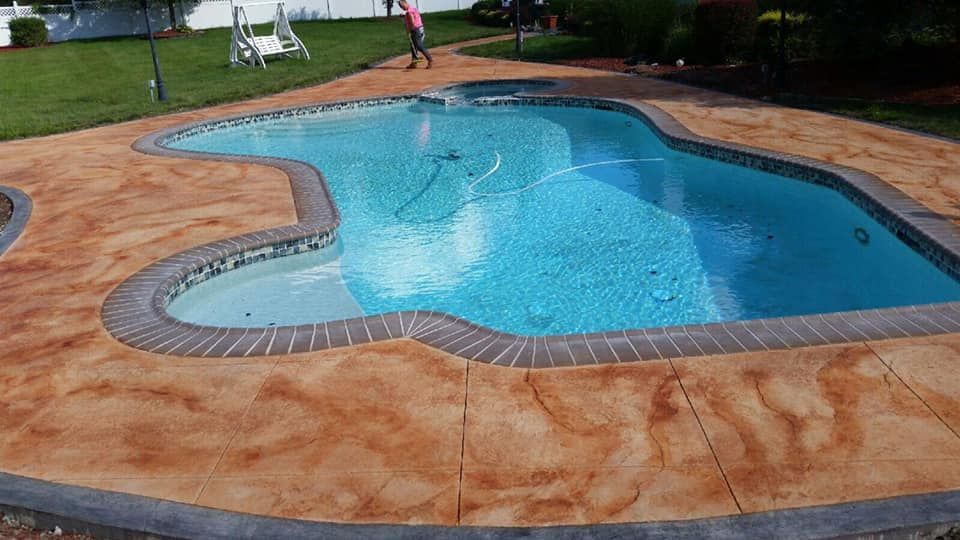 A large swimming pool is surrounded by a concrete patio.