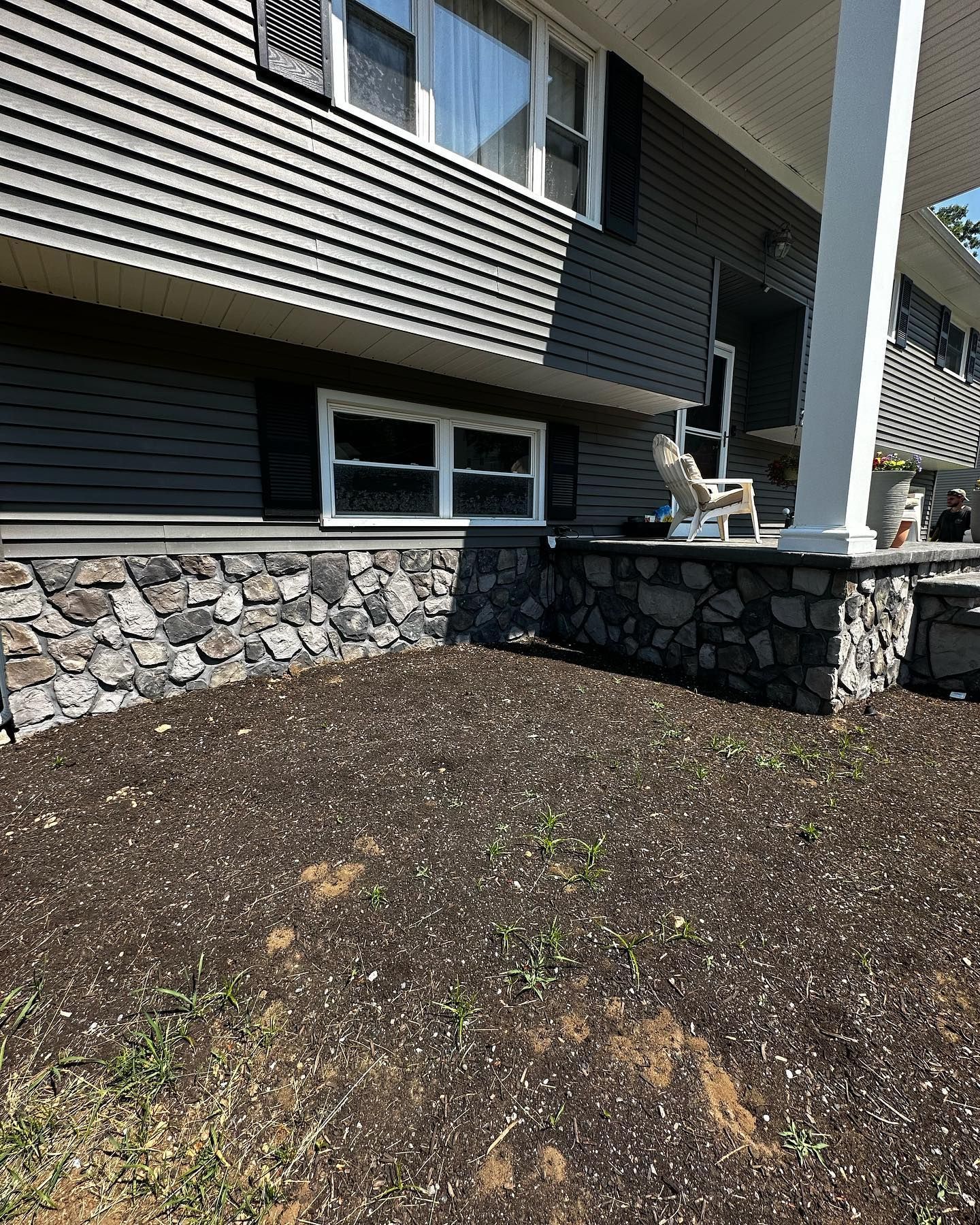The front of a house with a stone wall and a porch.