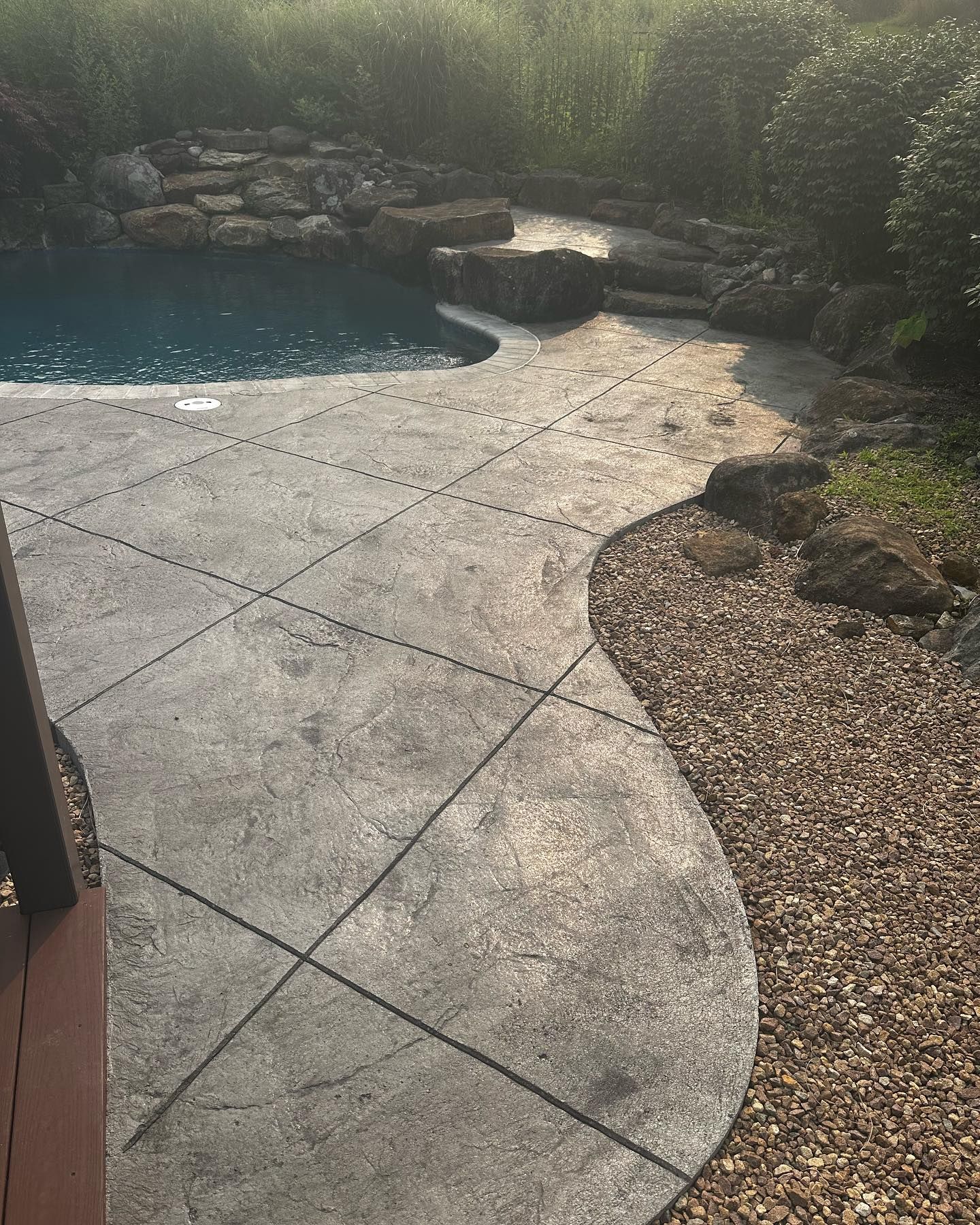 A concrete patio with a swimming pool in the background.