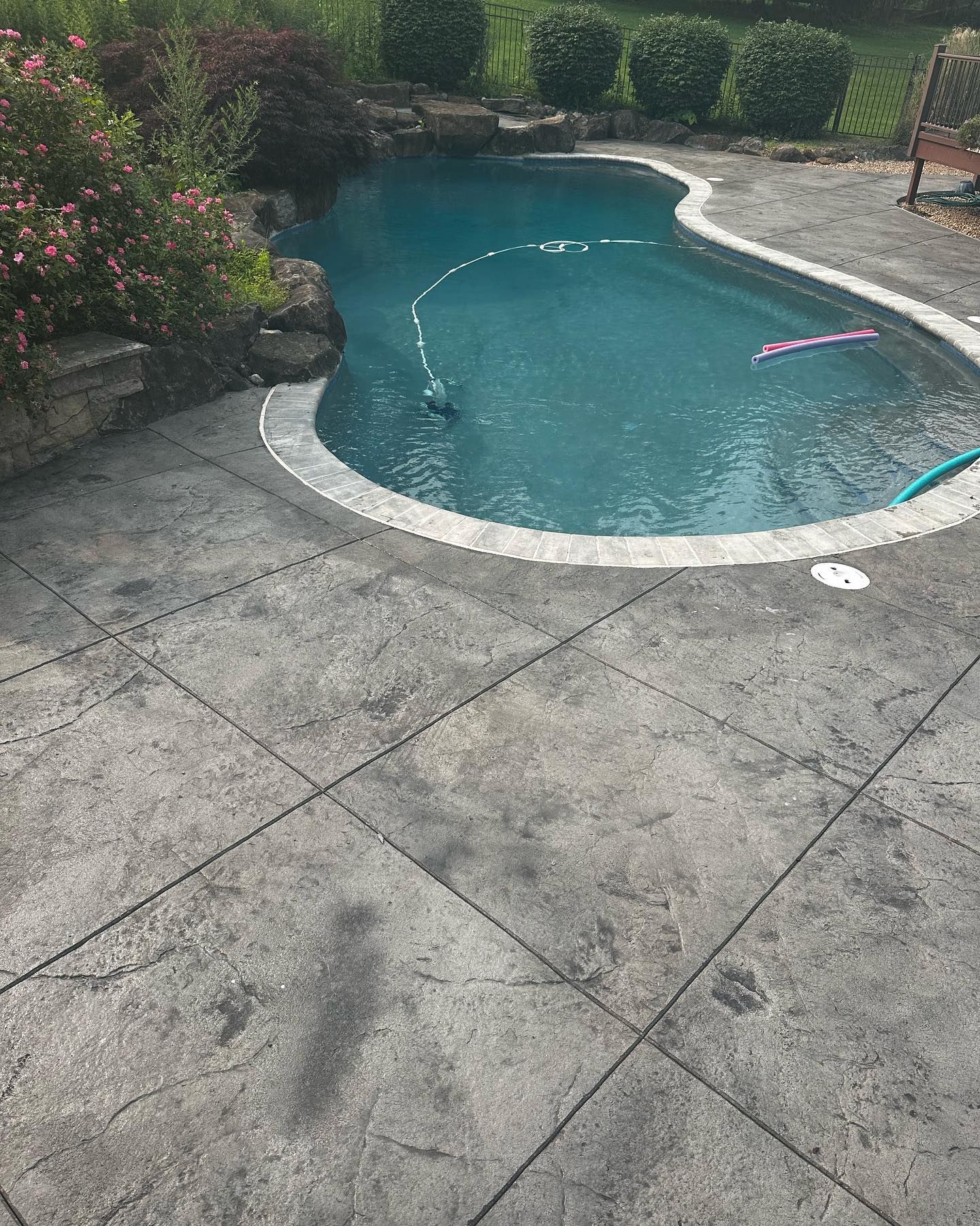 A large swimming pool is surrounded by a concrete patio.