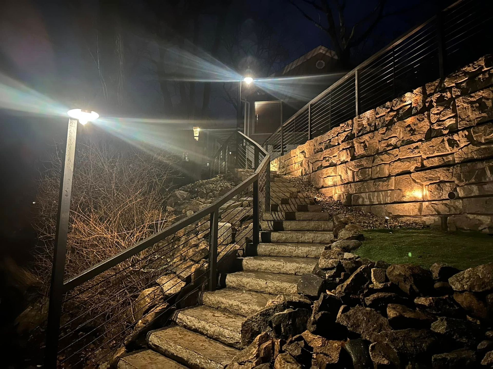 A set of stairs leading up to a stone wall at night.