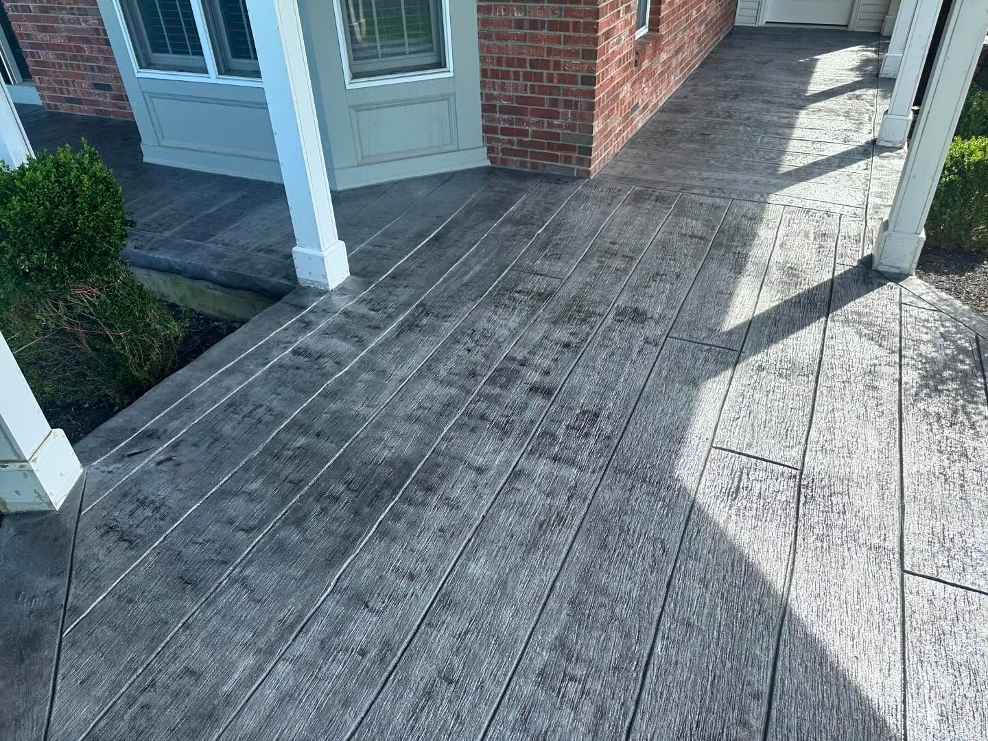 A concrete porch with a brick building in the background.