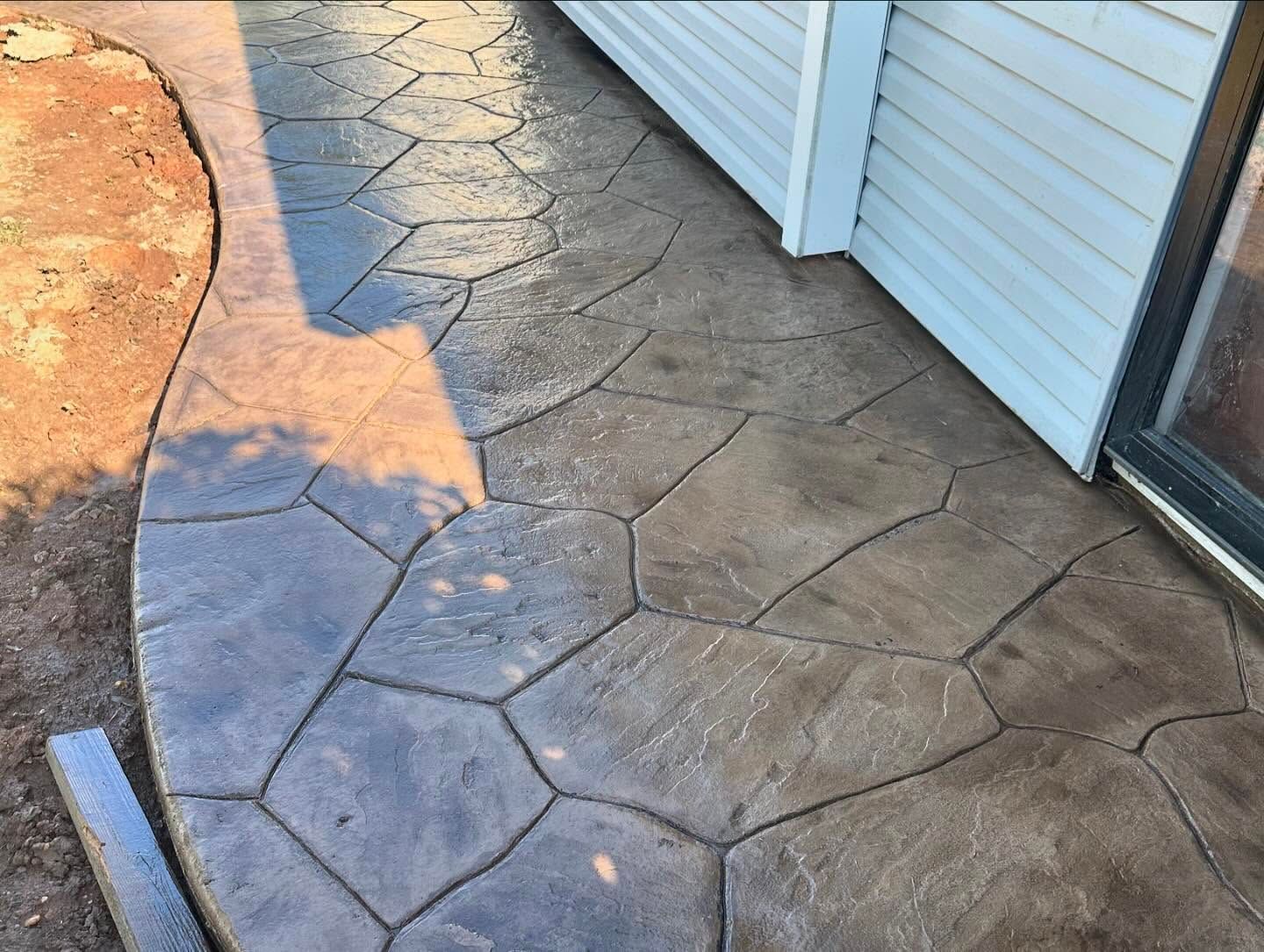 A concrete walkway leading to a house with a white house in the background.