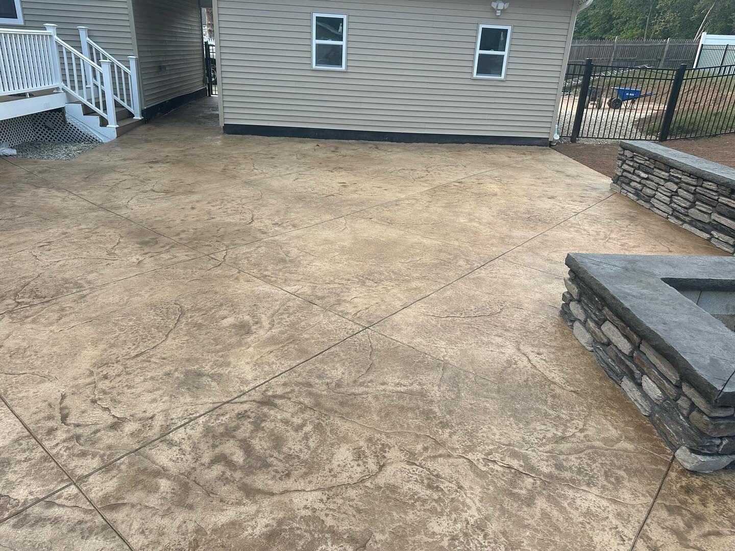 A concrete patio with a fire pit in front of a house.