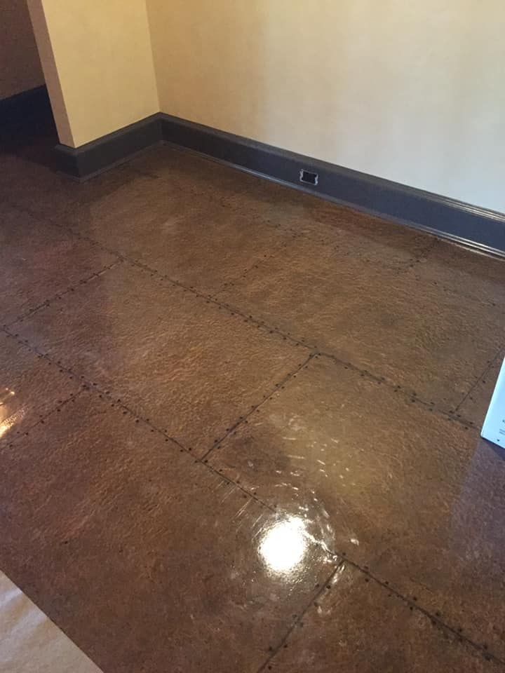 A brown tile floor in a room with a white wall
