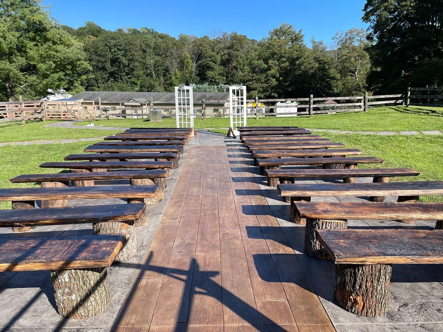 A row of wooden benches lined up on a brick walkway in a field.