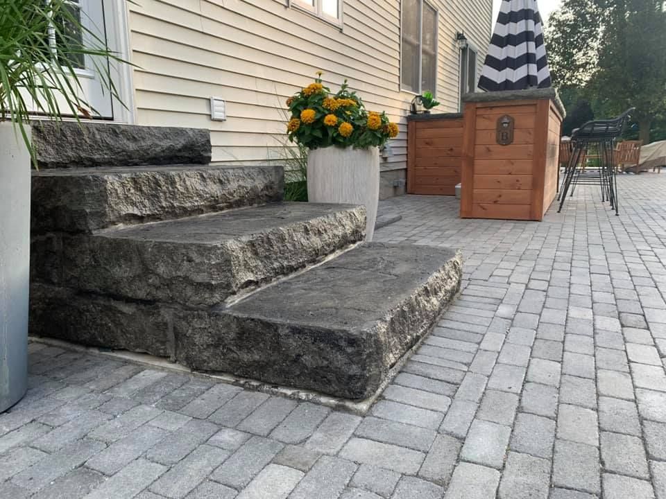 A stone staircase leading up to a patio with flowers in a pot.