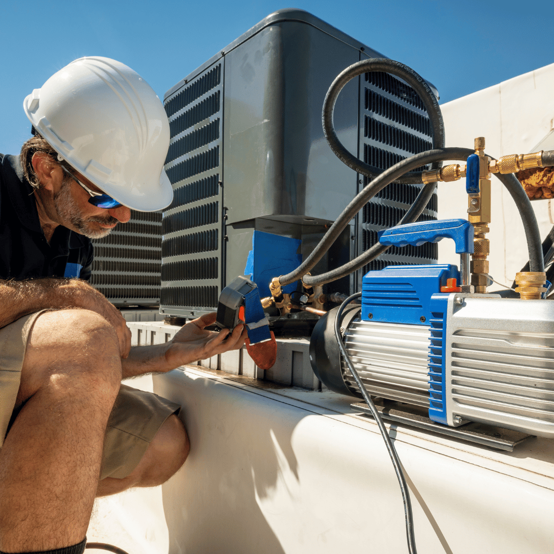 A man wearing a hard hat is working on an air conditioner