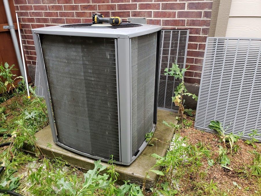 An air conditioner is sitting on the side of a brick building.