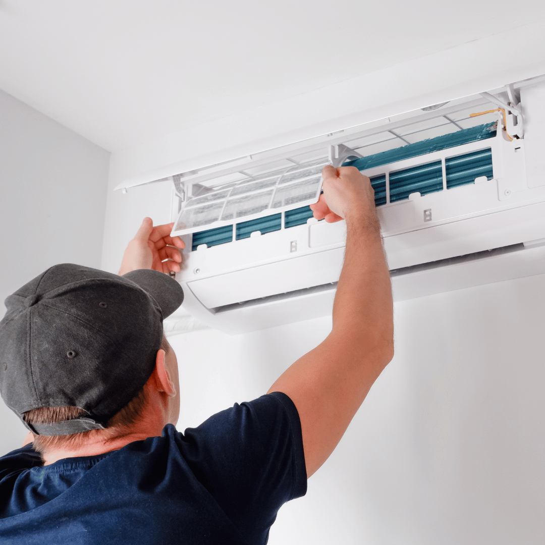 A man is fixing an air conditioner on the wall.