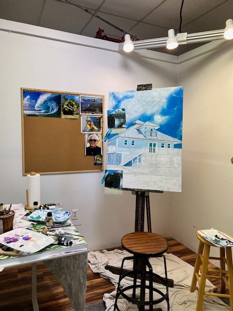 A painting of a house is on an easel in an art studio