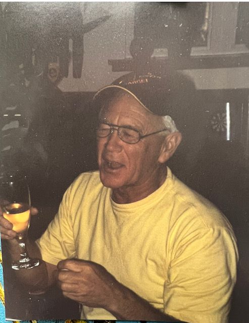 A man in a yellow shirt is holding a glass of wine