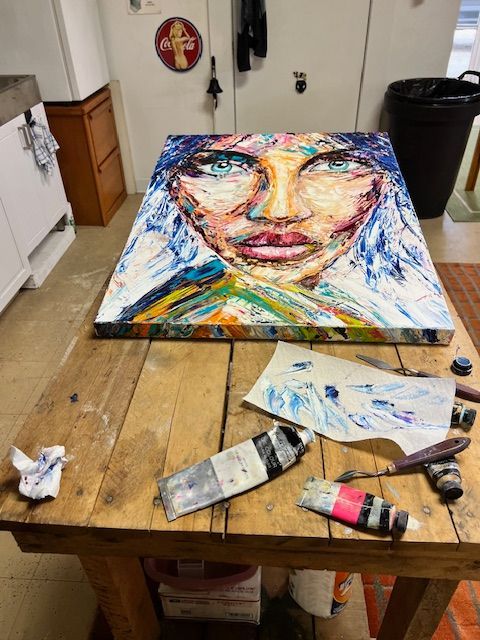 A painting of a woman 's face is on a wooden table.