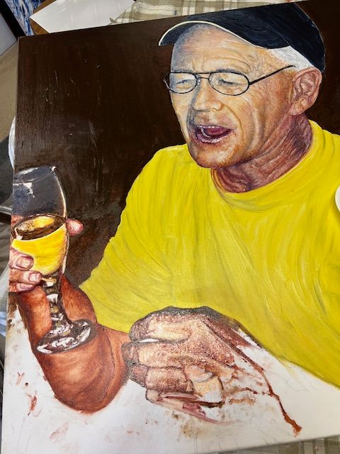 A man in a yellow shirt is holding a glass of wine