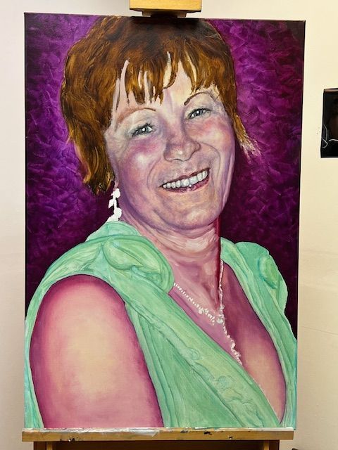 A painting of a woman in a green dress on an easel