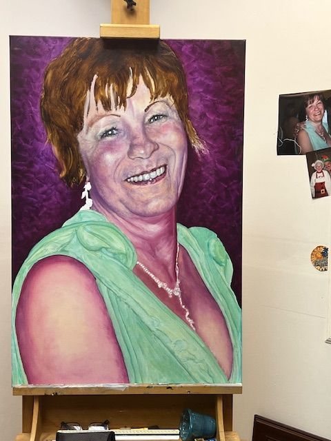 A painting of a woman in a green dress is on an easel