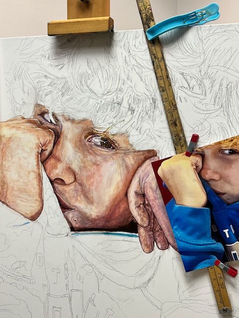 A painting of a child 's face is being painted on an easel.