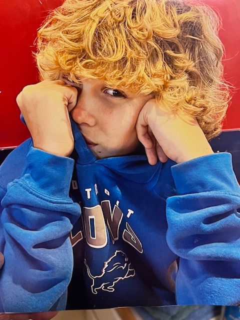 A young boy wearing a blue hoodie with the word love on it