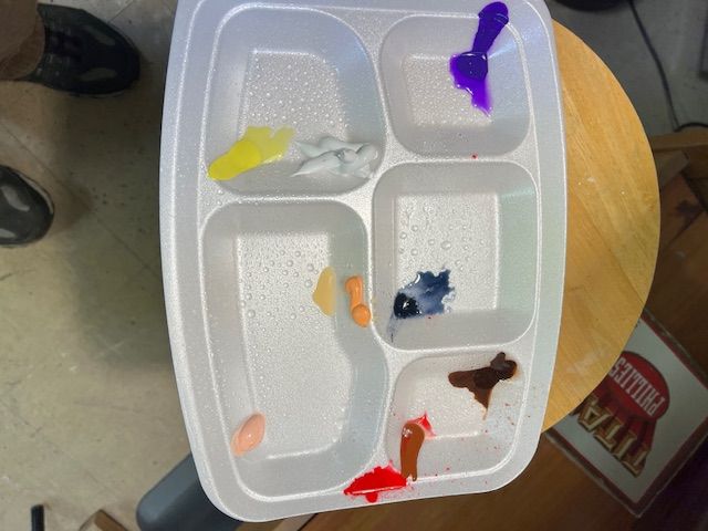A styrofoam tray filled with different colored objects on a table