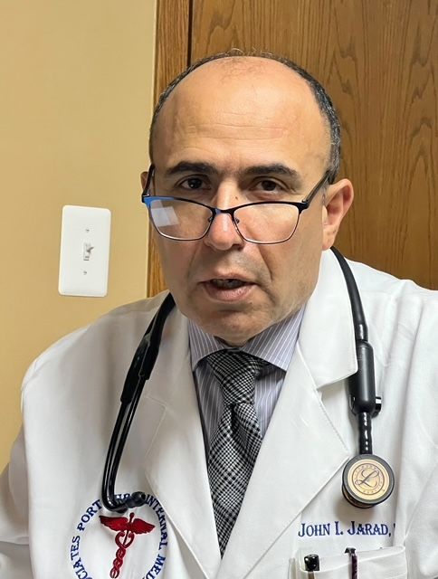 A doctor with a stethoscope around his neck is wearing glasses and a white coat