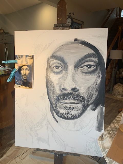 A painting of snoop dogg is being painted on an easel