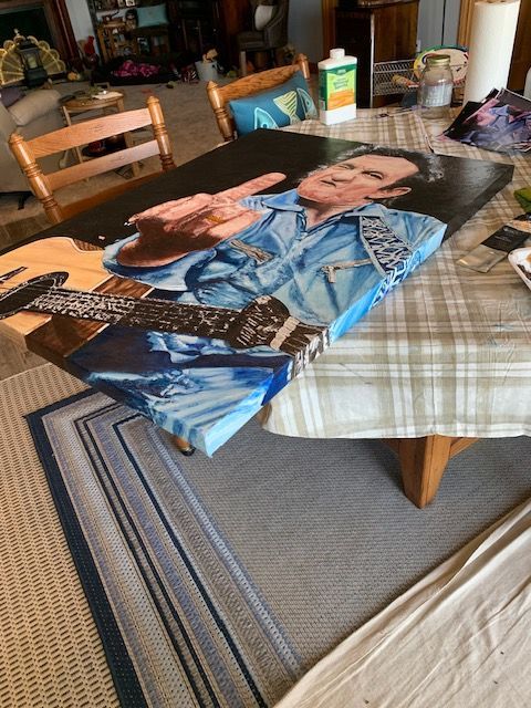A painting of a man playing a guitar is on a table.