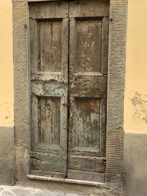 An old wooden door with a stone frame on a yellow wall
