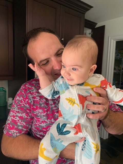 A man is holding a baby in his arms and kissing it on the cheek.