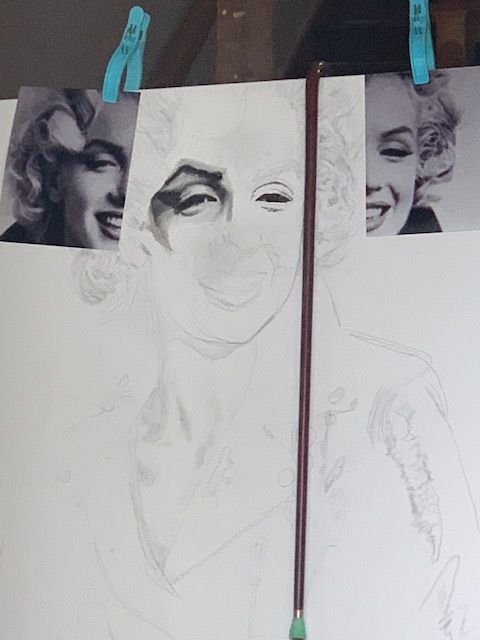 A drawing of marilyn monroe is hanging on a wall