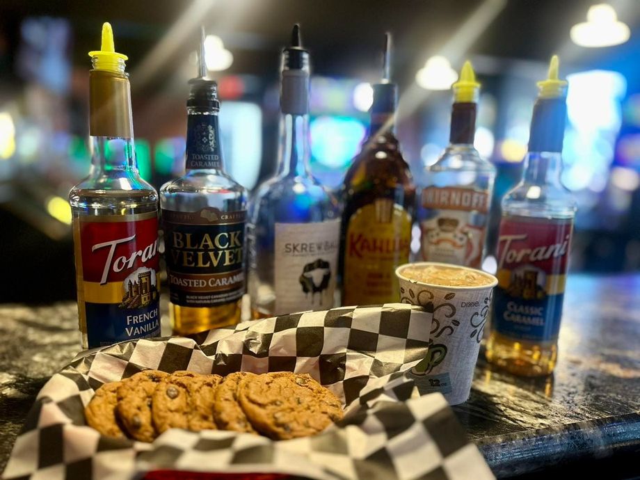 A basket of cookies and bottles of liquor on a table.