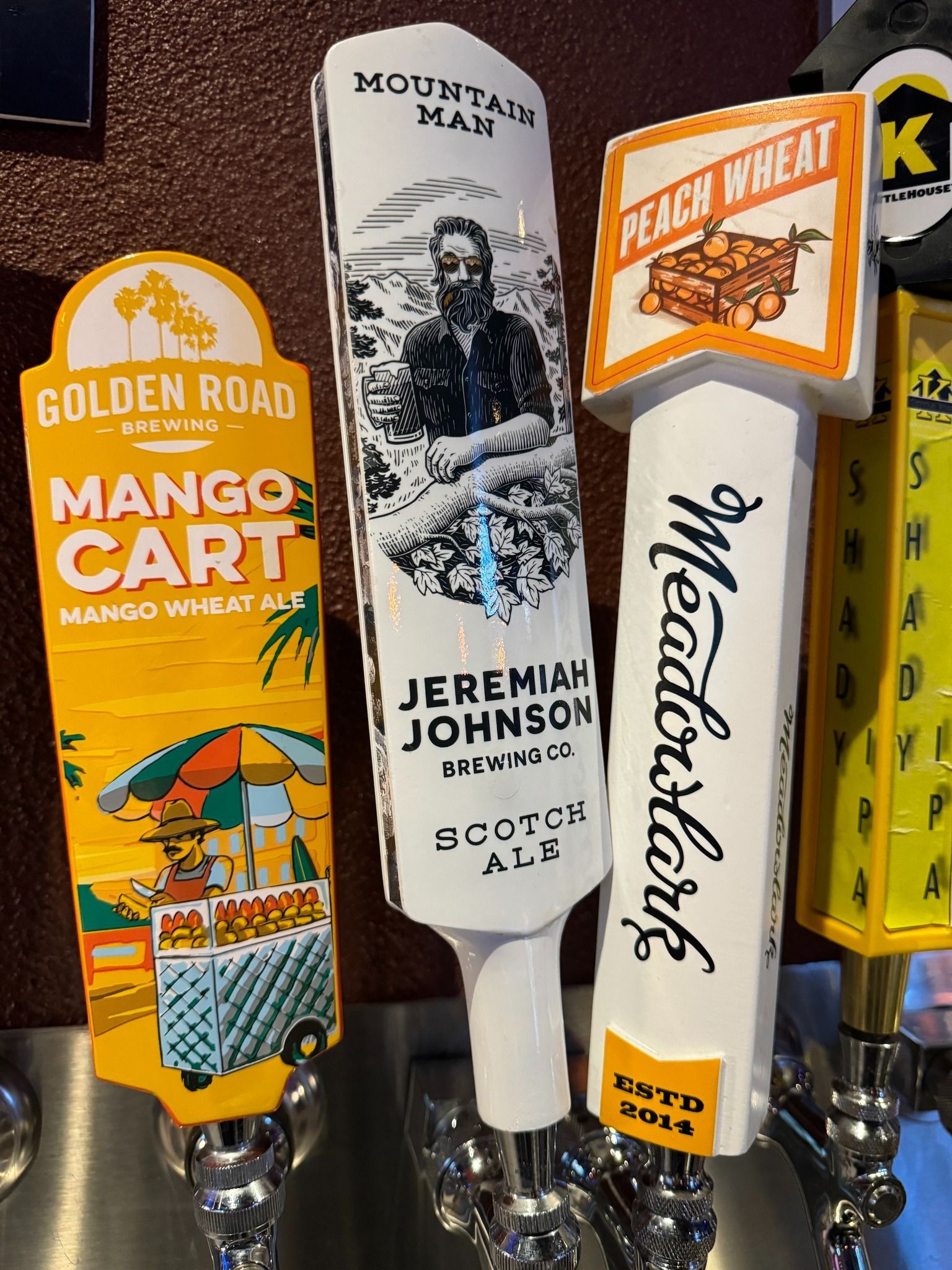 A row of beer taps including mango cart and peach wheat