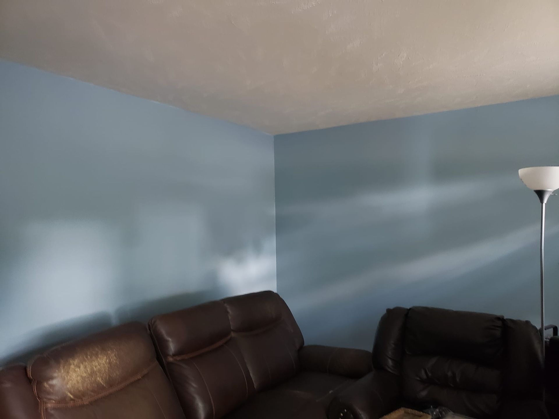 A living room with a couch and two chairs and a lamp