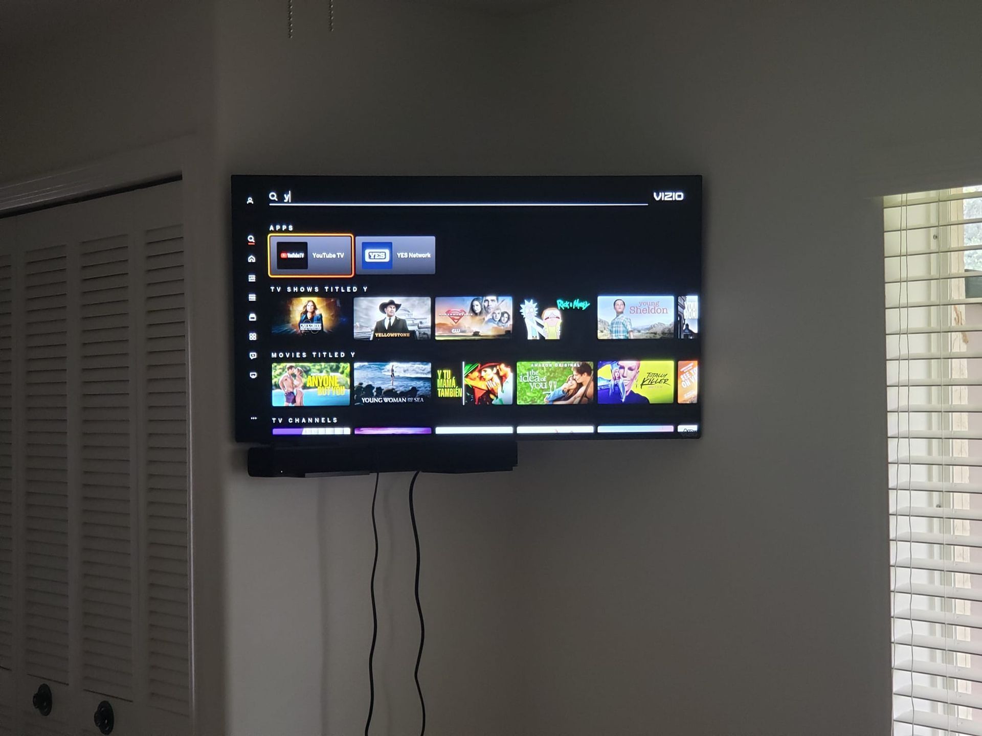 A flat screen tv is mounted on a wall and shows a variety of shows