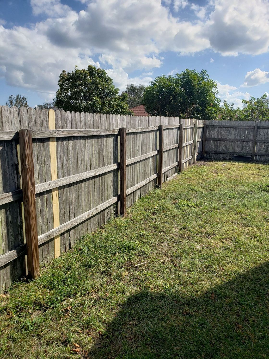 A wooden fence is in the middle of a grassy yard.