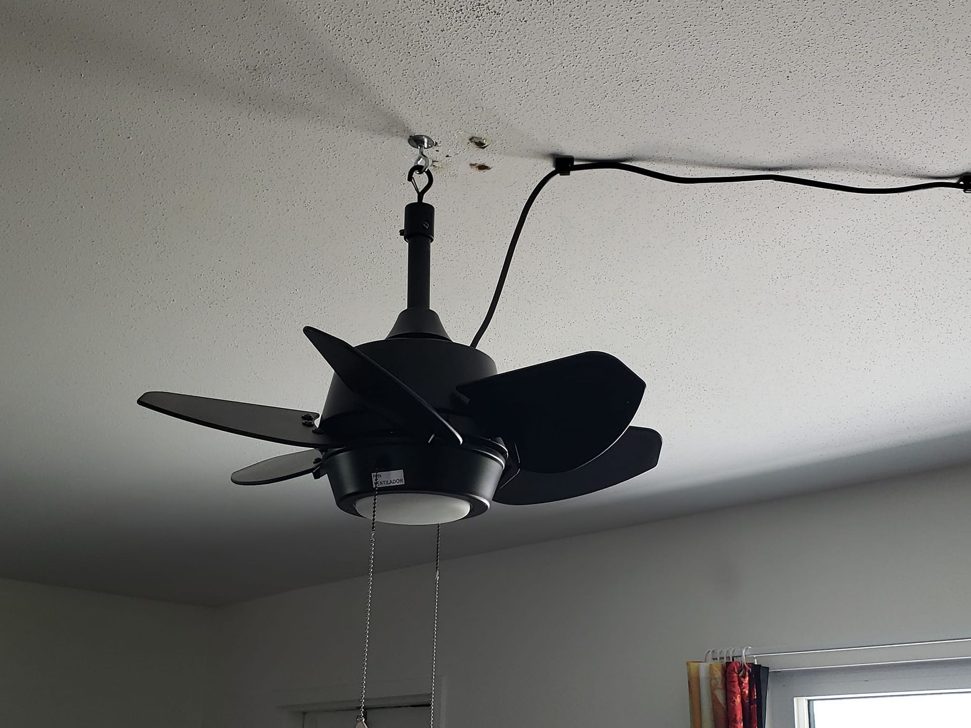 A black ceiling fan is hanging from the ceiling in a room