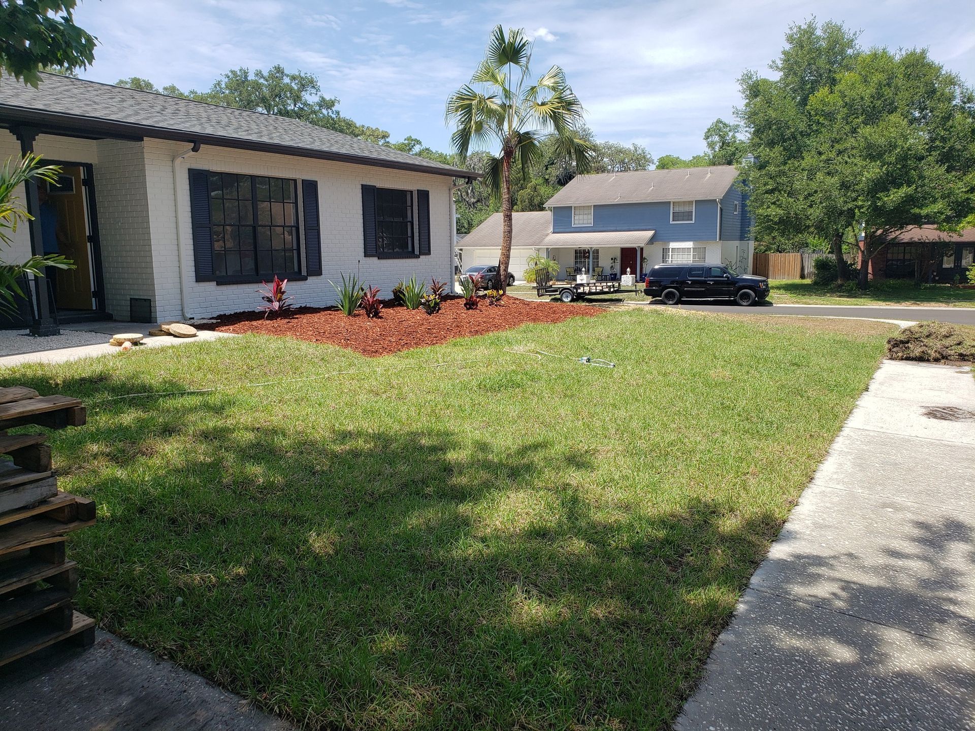 A large lawn in front of a house with a blue house in the background.