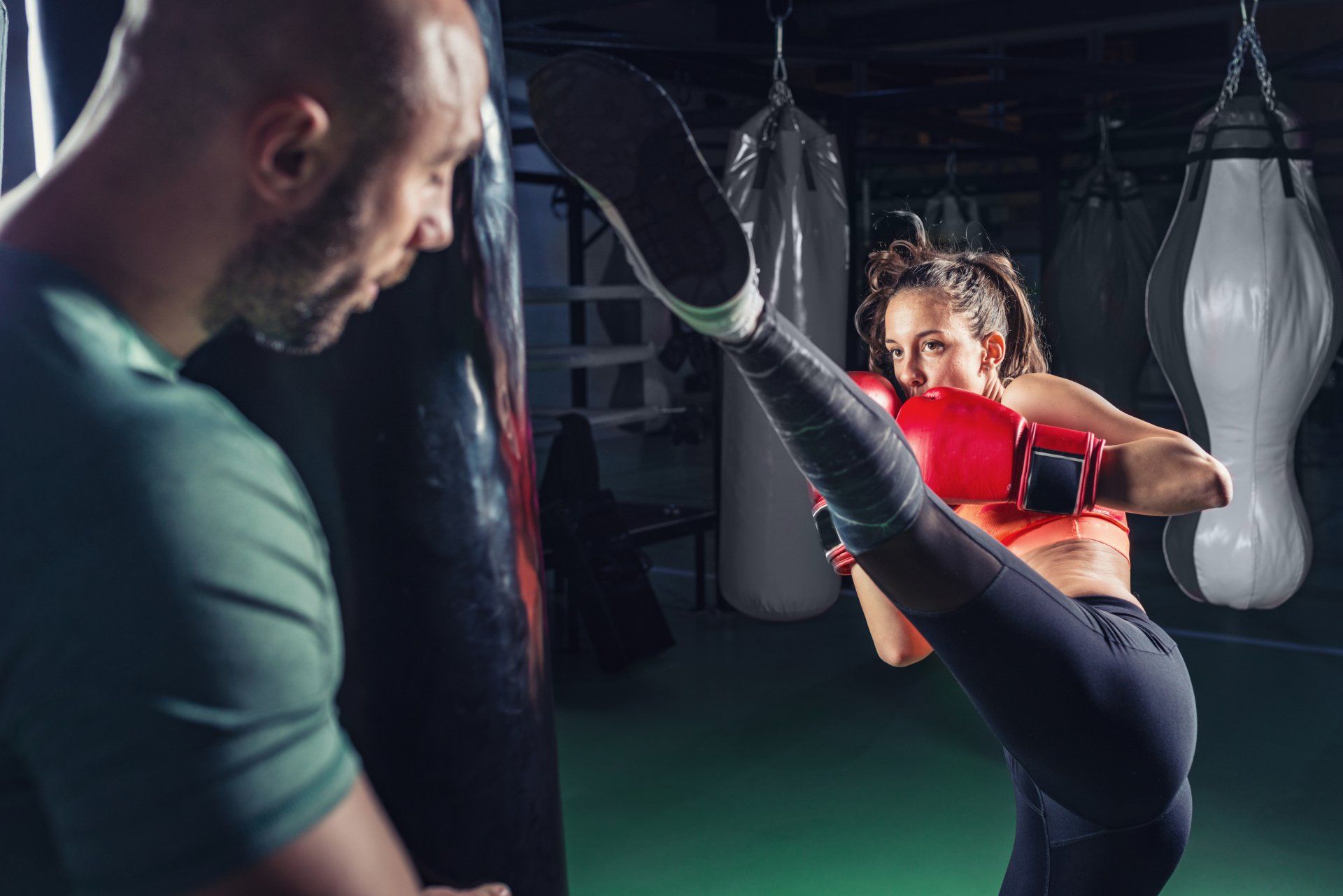 One on one kickboxing training with coach by holding the bag while trainee is kicking as high s she could
