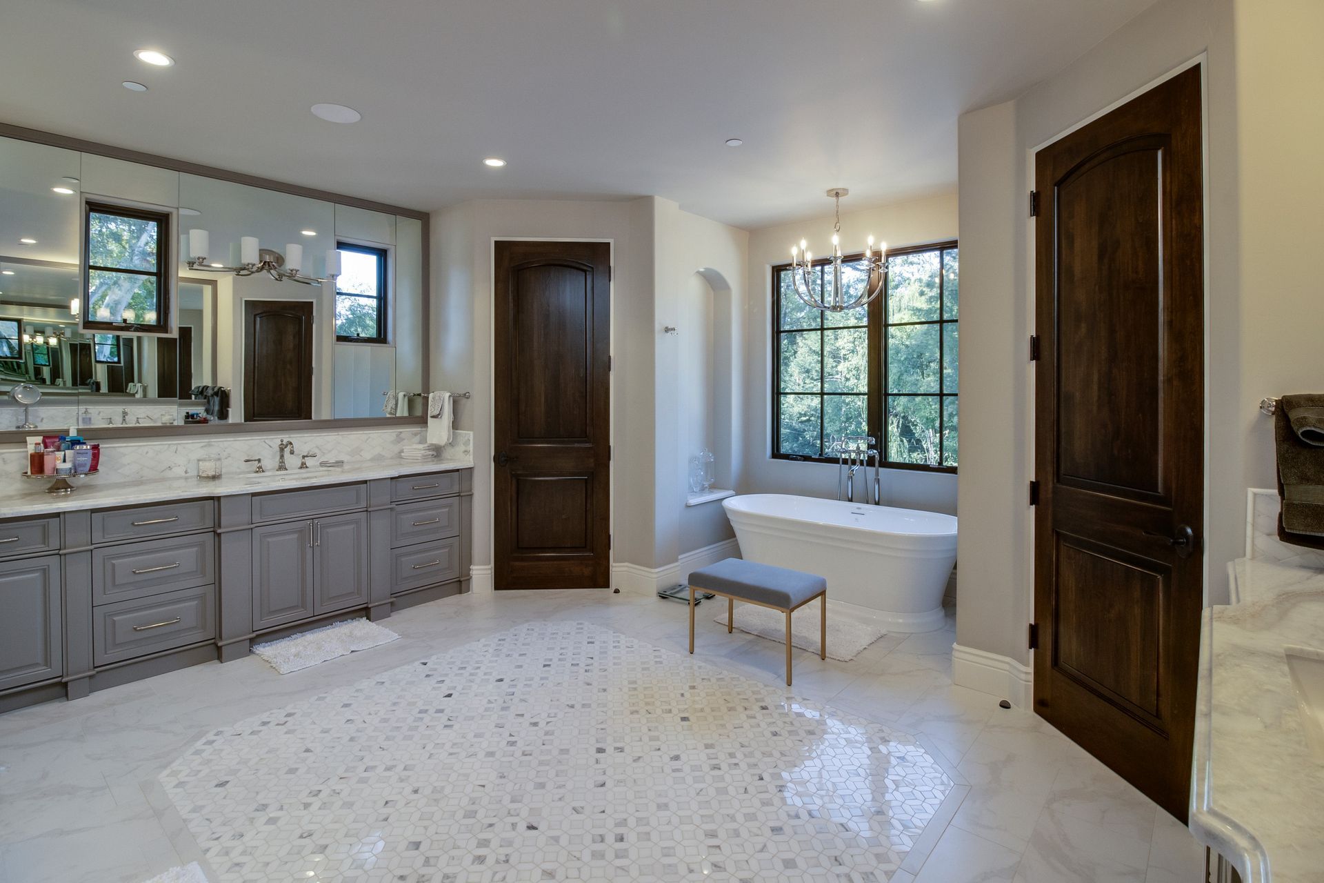 A bathroom with two sinks , a tub and a bench.