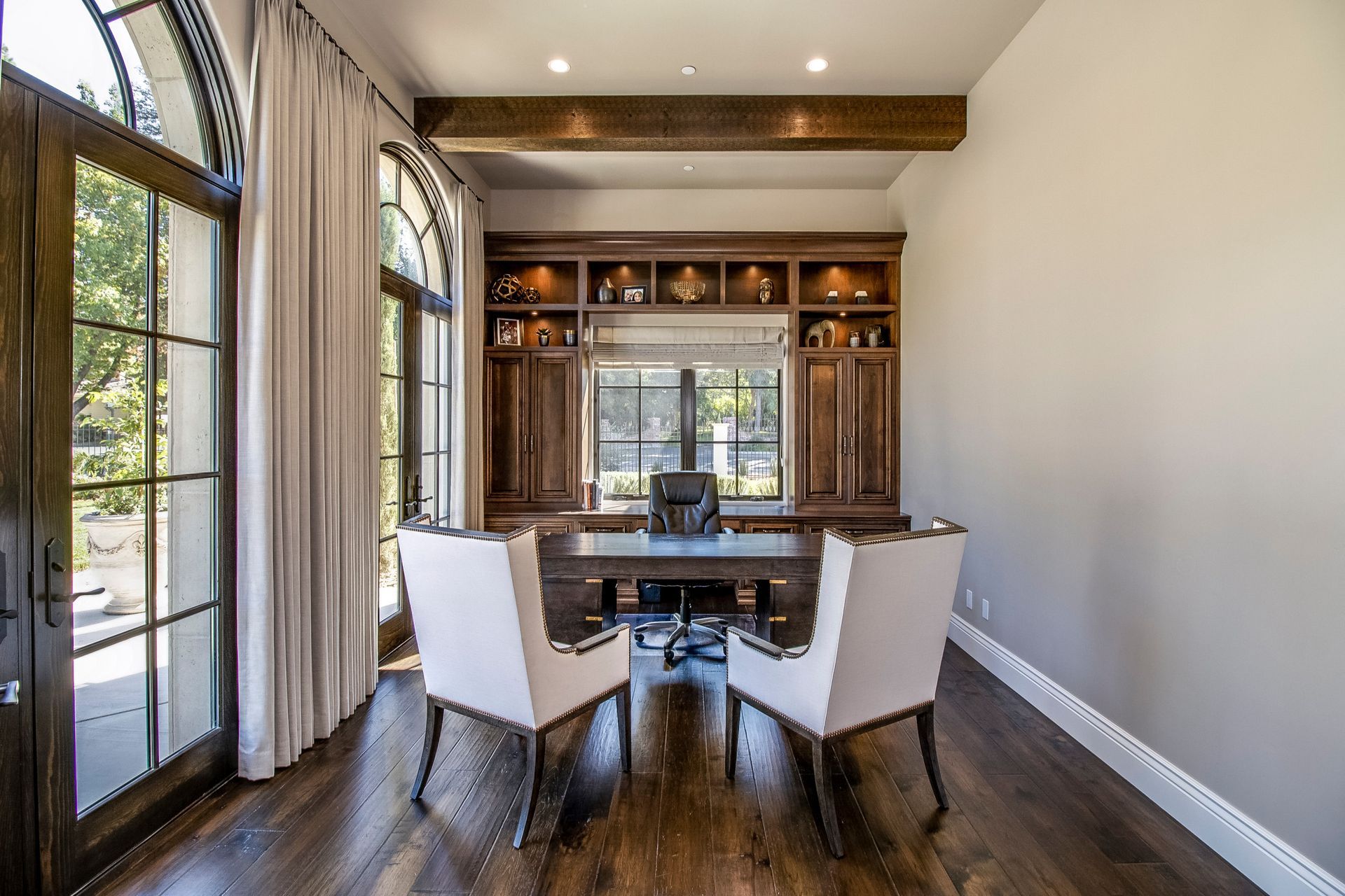 A home office with a desk and chairs and a large window.
