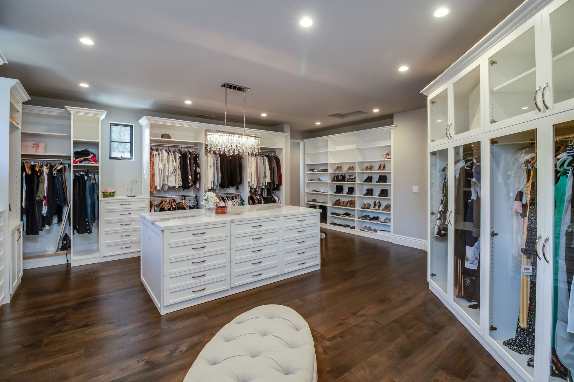 A large walk in closet with lots of clothes and shoes.